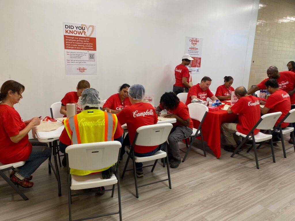 Campbell employees decorate tote bags at tables