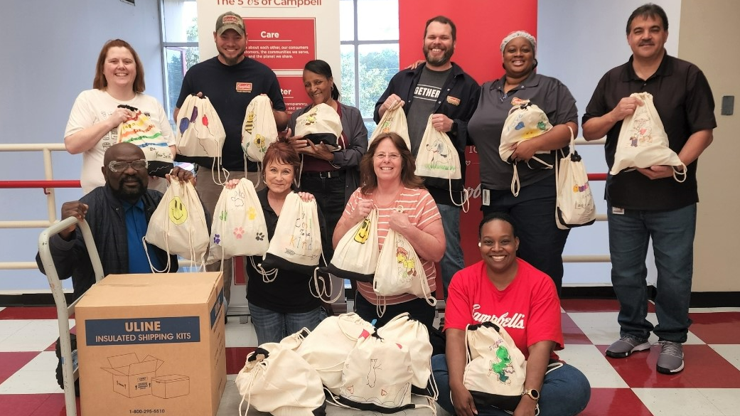 Employees in Maxton pose with filled backpacks