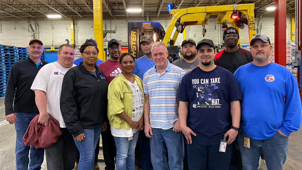 Employees pose on plant floor